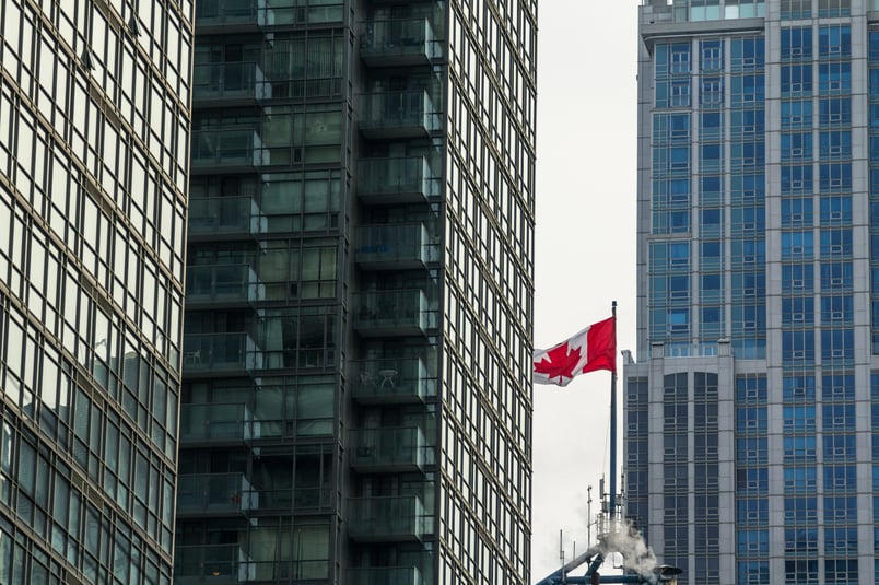 The Canadian flag between two buildings.