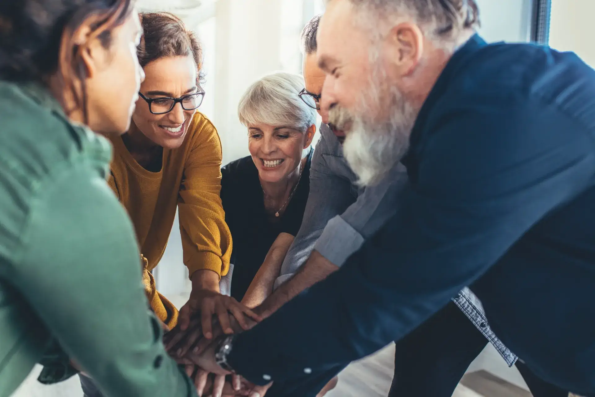 Smiling colleagues join hands in an office meeting